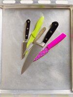 Various kitchen knives on a baking tray