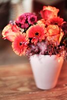 Herbstlicher Blumenstrauß in weisser Vase auf Holztisch