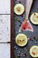 A raw fish, lemon slices, thyme, pink pepper and coarse sea salt