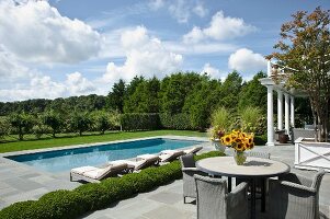 Outdoor Sitzgruppe auf Terrasse mit angrenzendem Pool in weiter Parklandschaft