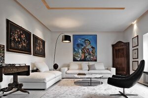 White living room in eclectic mixture of antique and modern elements; antique floral still-life paintings and modern oil painting on walls