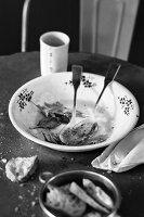 A used salad bowl, a napkin and the remains of bread on a table