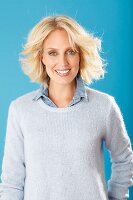 A young blonde woman wearing a denim shirt and white cashmere jumper