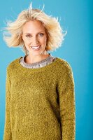 A young blonde woman wearing an olive green knitted jumper