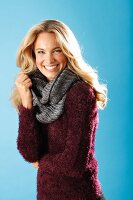 A young blonde woman wearing a burgundy knitted jumper and a grey scarf