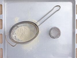 A sieve and a tin of icing sugar