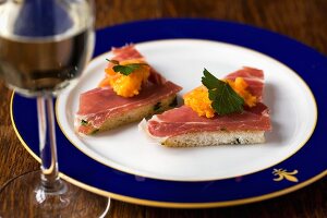Toast triangles topped with smoked ham and carrot cream