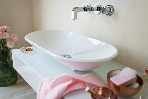 A designer console basin on a washstand with a glass surface and a wall tap