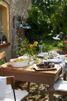 Mit Muscheln, Pommes und Zitronenscheiben gedeckter Holztisch im Garten eines französischen Landhauses