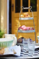 Vintage Etagere mit Feigen, Äpfeln und Aprikosen auf Frühstückstisch im Garten