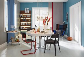 An elegant dining room with various different chairs around a round table with a classic winged armchair in the corner in the background