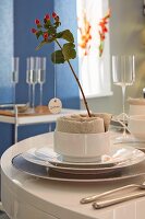 A name tag on a sprig of St. John's Wort and a napkin in a bowl as part of a place setting