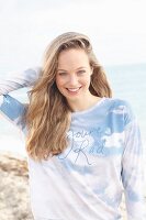 Junge, blonde Frau mit Langarmshirt am Meer