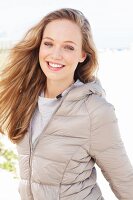 Young blonde woman outside wearing a beige quilted jacket