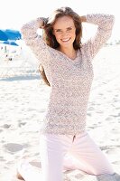 Junge Frau mit langen Haaren in gestricktem Pulli am Strand