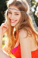 A young woman wearing an orange beach dress and head jewellery