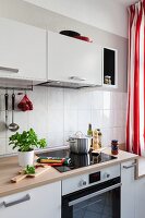 Detail of a kitchen counter with an induction hob with white wall cupboards above it in a renovated kitchen