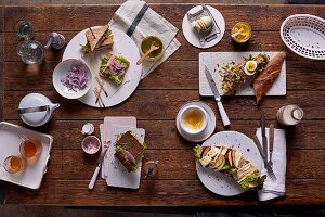 Vollkorn-Tramezzini mit Räucherforelle, Pumpernickel mit Schinken und Preiselbeerbutter, Thunfisch-Baguette mit Ei und Curry, Landbrot-Schnitte mit Camembert und Apfelspalten