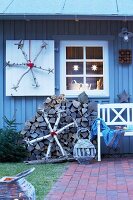 Homemade snowflakes made from silver birch against a grey-painted wooden house in the evening
