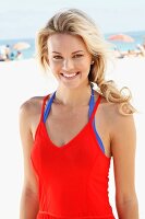 A young blonde woman on a beach wearing a red dress