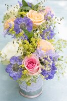 Two posies of roses and scabious in decorative tins