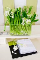 Glass vase of white hyacinths on shelf above desk calendar