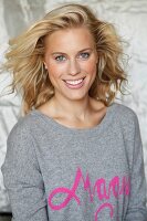 A blonde woman wearing a grey jumper with the word 'Magic' in pink