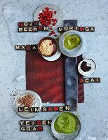 Still-life arrangement of goji berries, moringa, acai, maca, wheatgrass and flaxseed