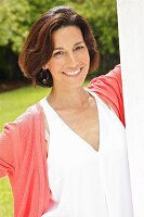 Dark-haired woman wearing top and cardigan in garden