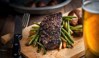 Rib-eye steak on a bed of mixed vegetables with potatoes