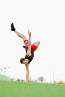 Mann im Einhand-Stand im Grünen vor Skyline