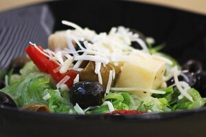 A mixed leaf salad with olives, peppers and cheese