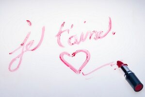 The words 'Je t'aime' and a heart drawn on a white surface with lipstick