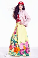 A young woman wearing a colourful outfit with a floral-patterned maxi skirt