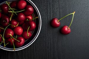 Cherries in a metal bowl on a black table