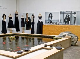 Grosses Wasserbassin mit Goldfischen im Atelier, im Hintergrund Schneiderpuppen mit eleganten, schwarzen Kleidern