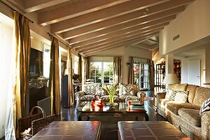 Leather ottomans and sofa set in open-plan interior with wood-beamed ceiling