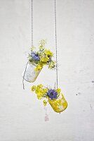 Jam jars covered in tissue paper hung from strings and used as vases