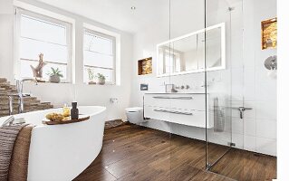 A modern bathroom with a warm, cosy atmosphere thanks to dark, wooden-style floor tiles and a free-standing oval bathtub