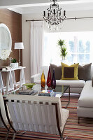 Living room with chandelier, white sofa and leather armchair