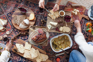 A person eating a picnic-style Christmas meal on a kilim rug