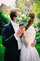 A bride and groom kissing behind the bride's bouquet