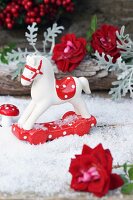Small rocking horse and toadstool ornaments and rose arranged on artificial snow
