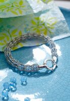 A beaded bracelet with a knitted encasing with blue beads next to it