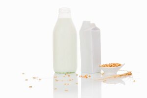 Grain milk in a bottle and a carton on a white surface