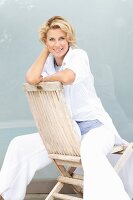 Blonde Frau sitzt rücklings auf Holzstuhl