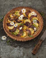 Yellow courgette tart with red onions and edible flowers
