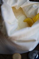 A linen sack of Italian type 00 flour with a scoop and pasta-making tools lying next to it