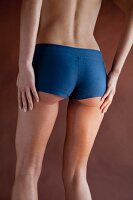 A woman wearing tight, blue, sporty shorts with her hands on her thighs