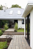 Terrassen und Wege mit Holzdielenbelag vor modernem Wohnhaus
